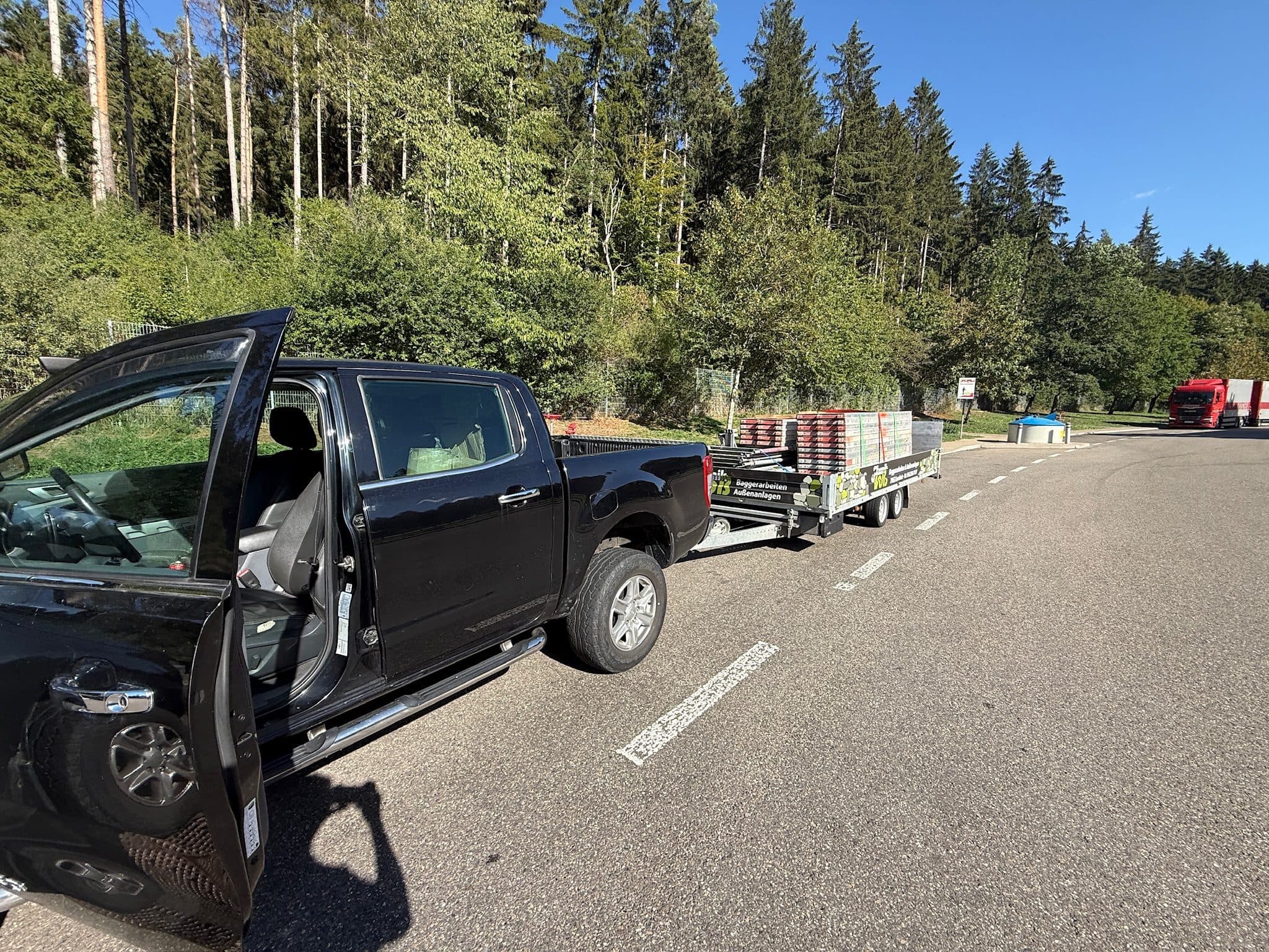 Pickup mit beladenem Gerüst-Anhänger auf dem Weg zur Baustelle